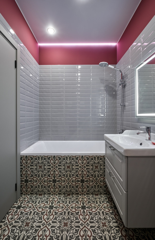 На фото: главный совмещенный санузел среднего размера со стиральной машиной в современном стиле с фасадами с выступающей филенкой, серыми фасадами, полновстраиваемой ванной, инсталляцией, серой плиткой, керамической плиткой, розовыми стенами, полом из цементной плитки, подвесной раковиной, разноцветным полом, гигиеническим душем, тумбой под одну раковину и подвесной тумбой с