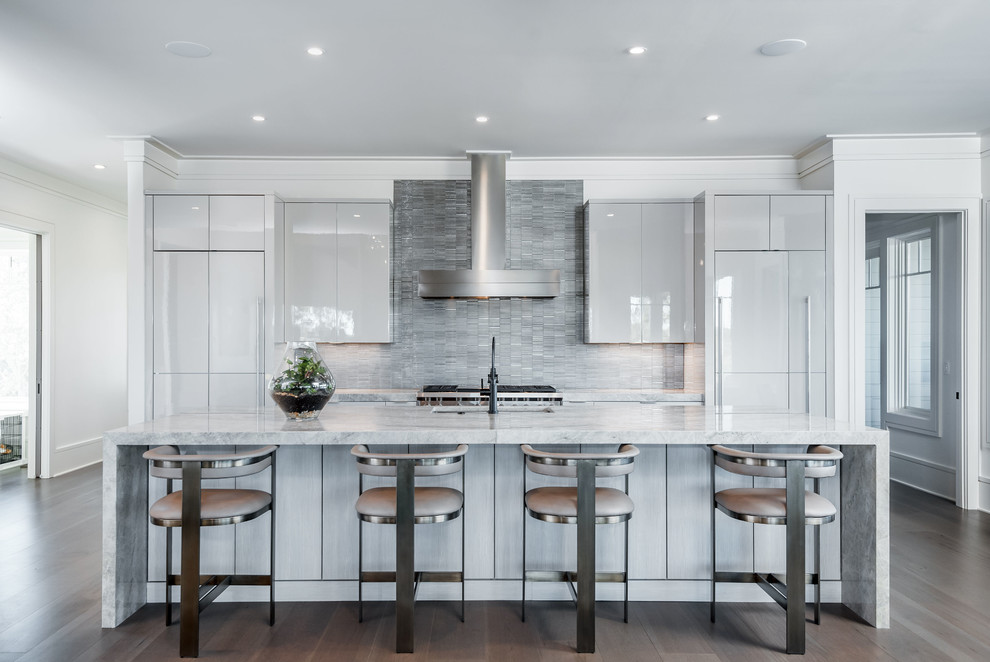 Contemporary galley open plan kitchen in Charleston with an undermount sink, flat-panel cabinets, grey splashback, medium hardwood floors, with island, brown floor, grey benchtop, beige cabinets, marble benchtops, metal splashback and panelled appliances.