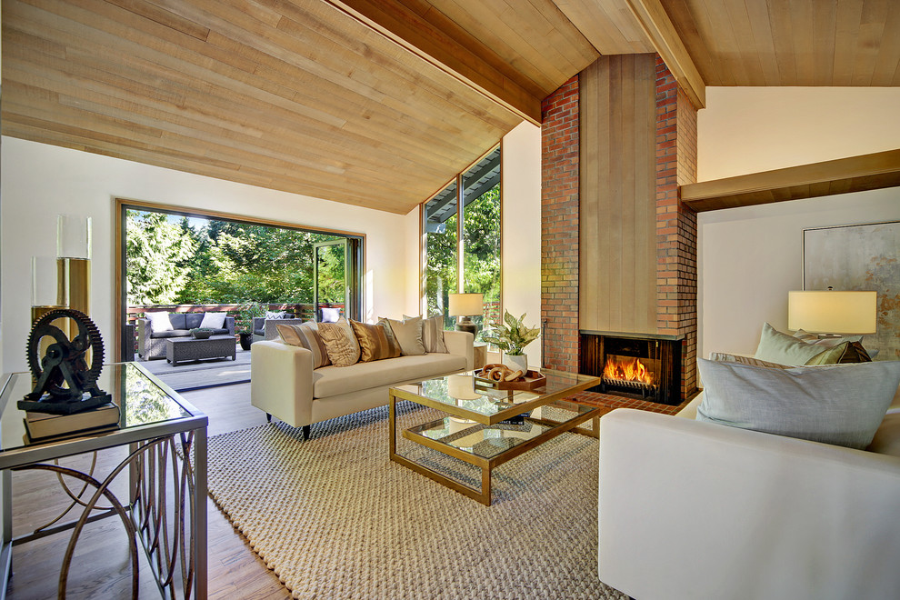 Photo of a large midcentury open concept living room in Seattle with white walls, medium hardwood floors, a corner fireplace, a brick fireplace surround and brown floor.
