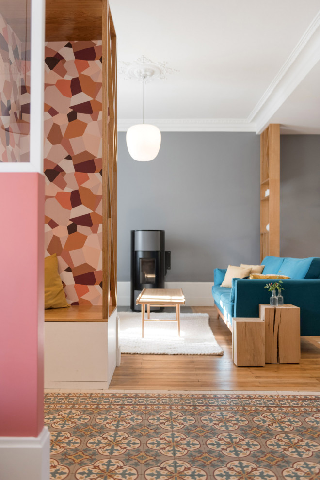 Diseño de sala de estar con biblioteca abierta actual grande con paredes rosas, suelo de cemento, chimenea de doble cara, marco de chimenea de piedra y suelo multicolor