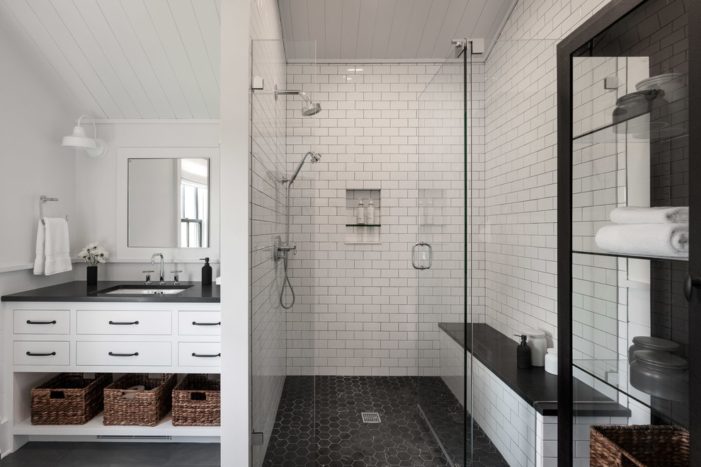 This is an example of a large country bathroom in New York with flat-panel cabinets, white cabinets, an open shower, white tile, subway tile, white walls, slate floors, an undermount sink, concrete benchtops, black floor, a hinged shower door and black benchtops.
