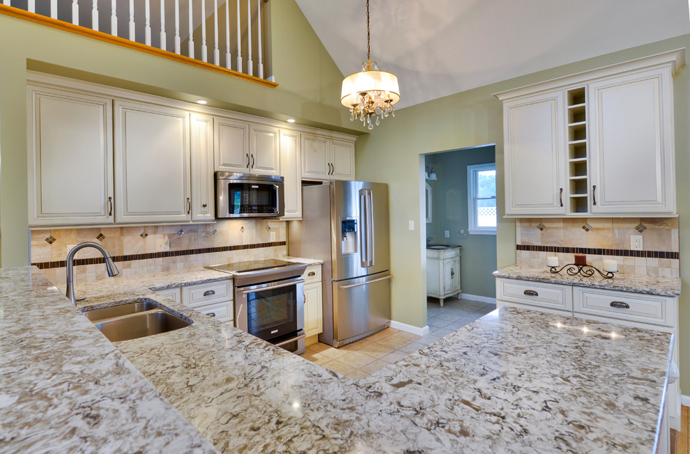 Inspiration for a mid-sized transitional galley open concept kitchen remodel with a double-bowl sink, beaded inset cabinets, white cabinets, wood countertops, beige backsplash, ceramic backsplash, stainless steel appliances and a peninsula