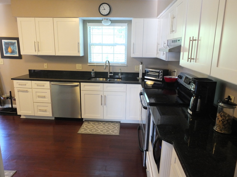 Example of a mid-sized trendy l-shaped dark wood floor enclosed kitchen design in Columbus with an undermount sink, shaker cabinets, yellow cabinets, granite countertops, beige backsplash, stainless steel appliances and no island