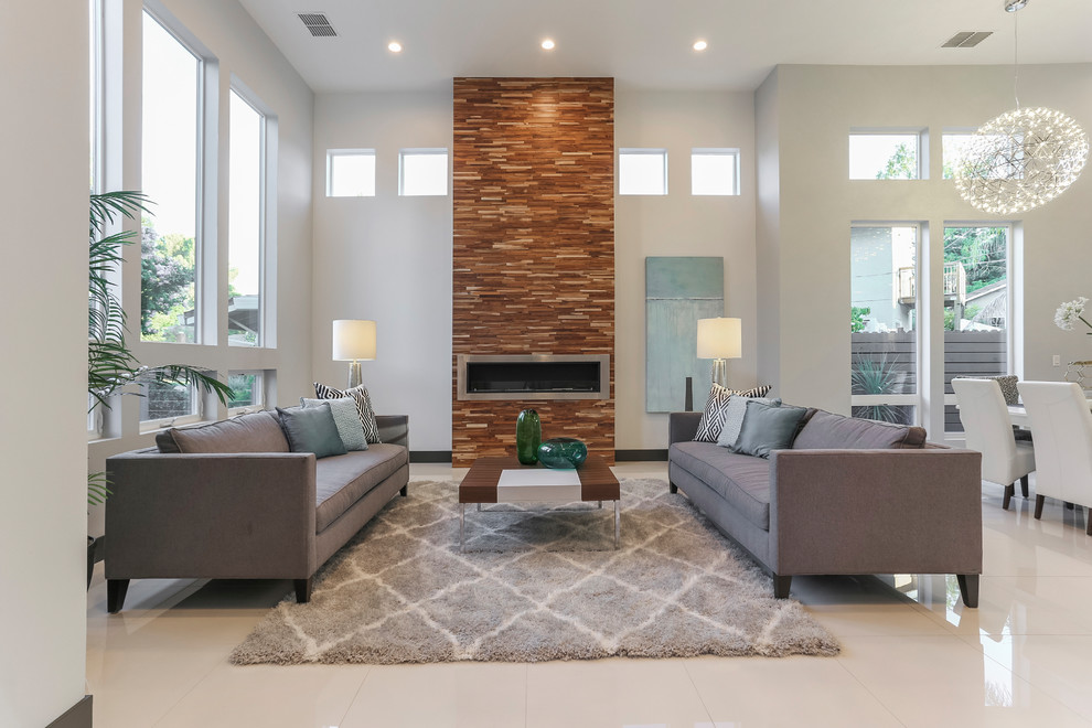 Photo of a large contemporary formal open concept living room in Sacramento with white walls, porcelain floors, a ribbon fireplace, a stone fireplace surround, no tv and white floor.