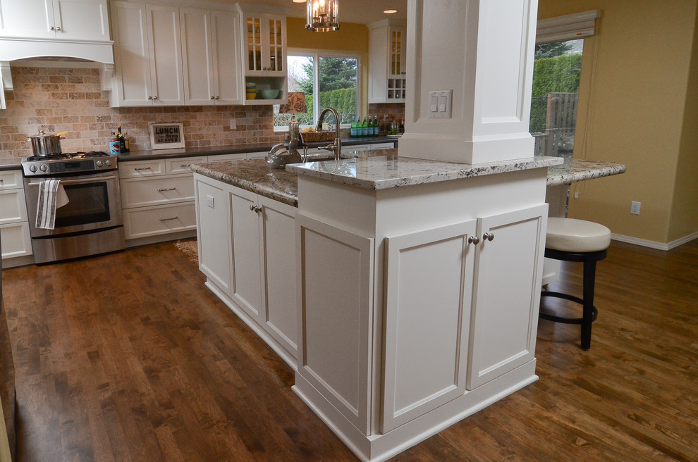 This is an example of a transitional eat-in kitchen in Portland with an undermount sink, recessed-panel cabinets, white cabinets, granite benchtops, beige splashback, stainless steel appliances, medium hardwood floors and with island.