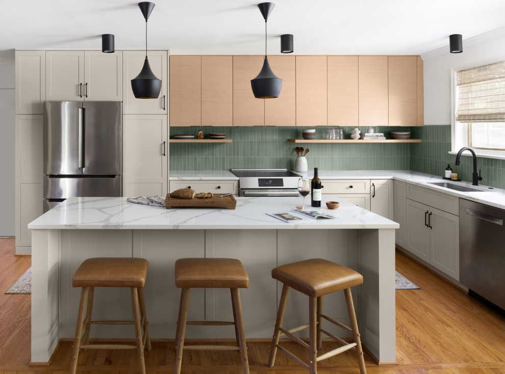 This is an example of a small midcentury l-shaped eat-in kitchen in DC Metro with an undermount sink, flat-panel cabinets, light wood cabinets, quartz benchtops, green splashback, ceramic splashback, stainless steel appliances, medium hardwood floors, with island, brown floor and white benchtop.