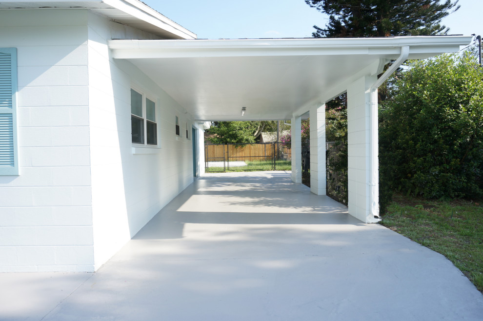 Photo of a mid-sized midcentury one-storey concrete white exterior in Orlando with a gable roof and a shingle roof.