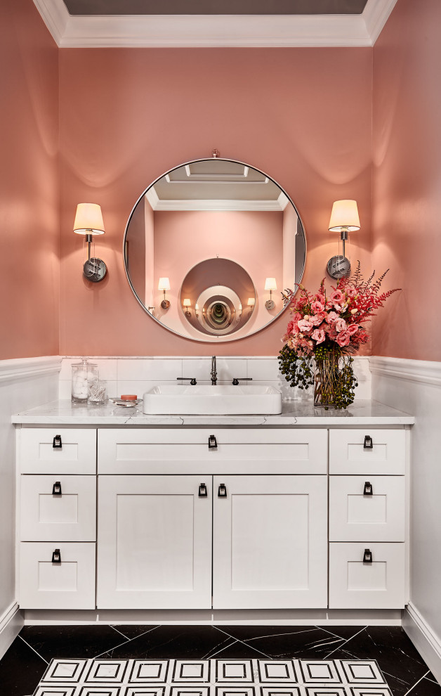 This is an example of a large classic ensuite bathroom in Denver with shaker cabinets, white cabinets, a freestanding bath, a corner shower, a two-piece toilet, white tiles, marble tiles, pink walls, porcelain flooring, a submerged sink, engineered stone worktops, black floors, a hinged door, white worktops, an enclosed toilet, double sinks, a built in vanity unit, a drop ceiling and wainscoting.