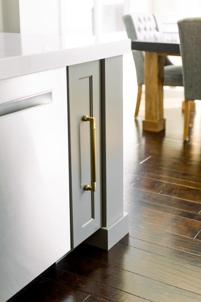 Example of a mid-sized transitional single-wall dark wood floor, brown floor and exposed beam eat-in kitchen design with an undermount sink, shaker cabinets, white cabinets, quartz countertops, white backsplash, subway tile backsplash, stainless steel appliances, an island and white countertops