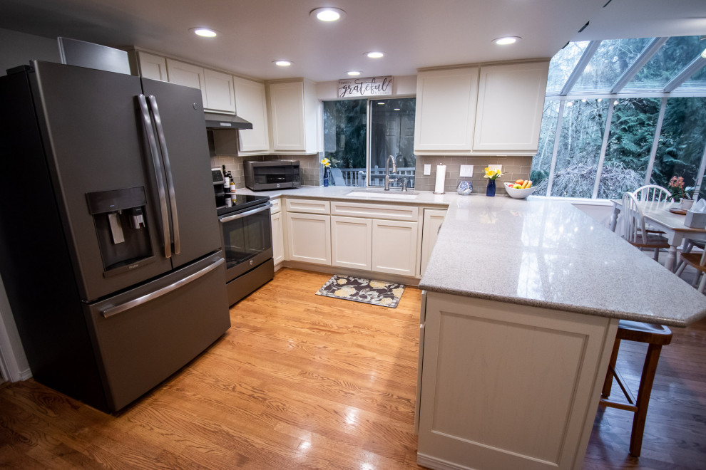 Example of a transitional u-shaped medium tone wood floor open concept kitchen design in Seattle with an undermount sink, shaker cabinets, white cabinets, quartz countertops, gray backsplash, glass tile backsplash, stainless steel appliances, a peninsula and multicolored countertops