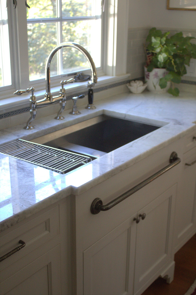 Eat-in kitchen - large transitional u-shaped medium tone wood floor eat-in kitchen idea in New York with a double-bowl sink, beaded inset cabinets, gray cabinets, quartzite countertops, gray backsplash, subway tile backsplash, black appliances and an island
