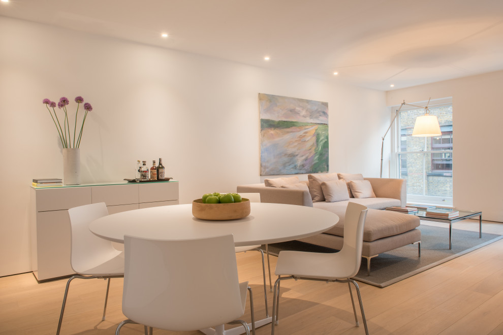 Design ideas for a contemporary open plan dining in London with white walls and light hardwood floors.
