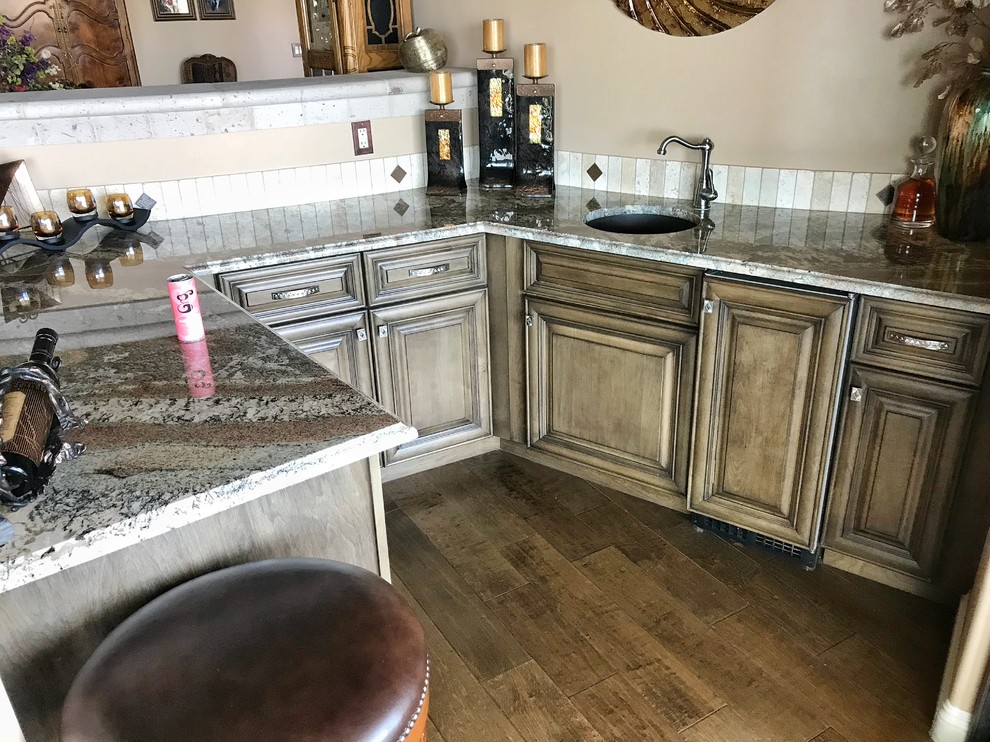 Inspiration for a large country single-wall open plan kitchen in Phoenix with an undermount sink, raised-panel cabinets, brown cabinets, beige splashback, travertine splashback, stainless steel appliances, travertine floors, multiple islands, beige floor, beige benchtop and granite benchtops.