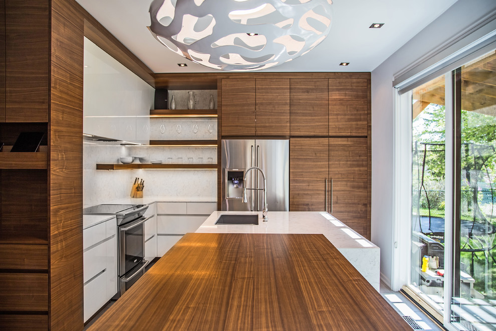 This is an example of a mid-sized midcentury l-shaped kitchen pantry in Calgary with an undermount sink, flat-panel cabinets, medium wood cabinets, quartz benchtops, white splashback, stainless steel appliances, ceramic floors and with island.