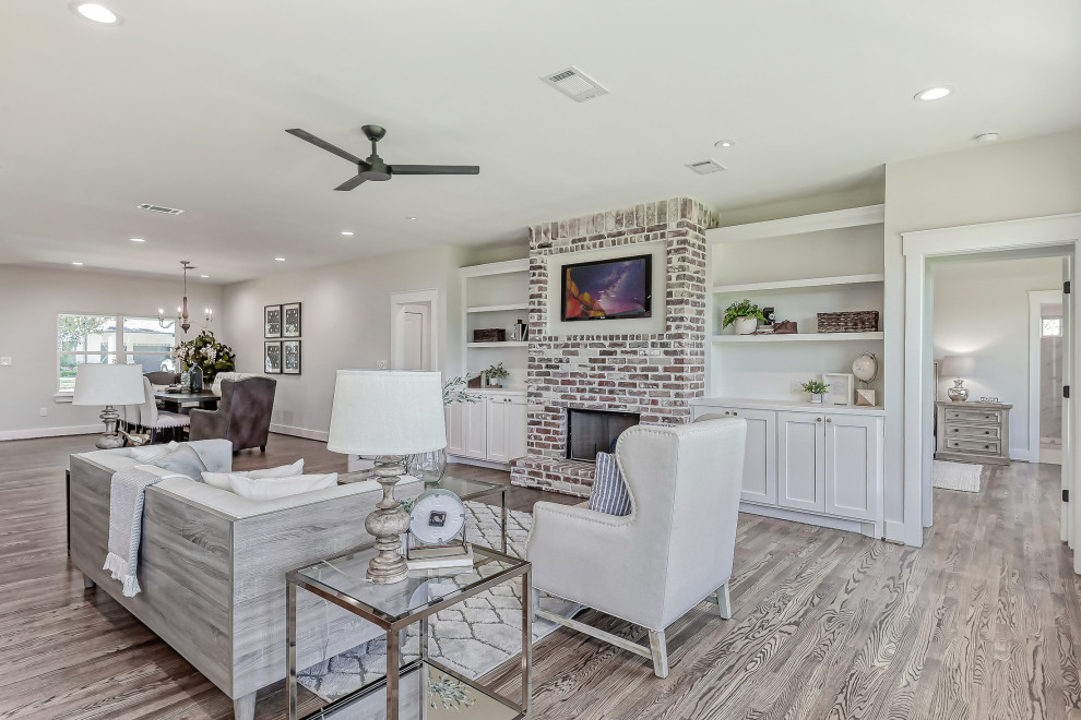 Mid-sized open concept family room in Houston with a standard fireplace, a brick fireplace surround and a wall-mounted tv.