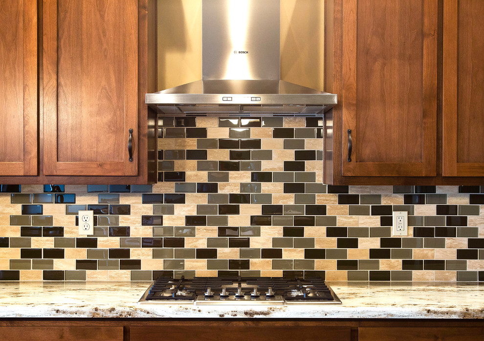 Example of a large classic kitchen design with shaker cabinets, medium tone wood cabinets, granite countertops, multicolored backsplash, subway tile backsplash and stainless steel appliances