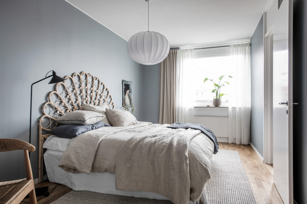 Scandinavian bedroom in Gothenburg with grey walls, medium hardwood floors and brown floor.