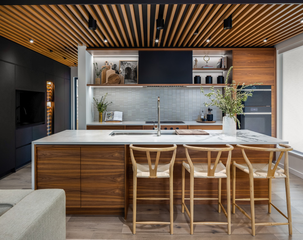 Expansive contemporary single-wall eat-in kitchen in Vancouver with an undermount sink, flat-panel cabinets, medium wood cabinets, quartz benchtops, white splashback, matchstick tile splashback, panelled appliances, light hardwood floors, with island, beige floor and white benchtop.
