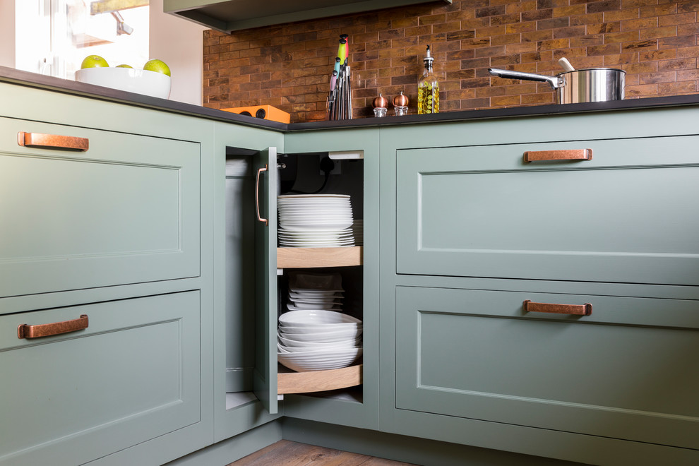 Mid-sized traditional u-shaped eat-in kitchen in Kent with a farmhouse sink, shaker cabinets, green cabinets, quartz benchtops, metal splashback, linoleum floors, a peninsula and green floor.