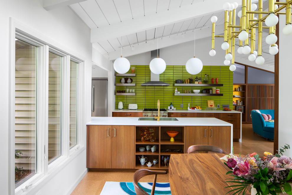 This is an example of a midcentury kitchen/diner in New York with flat-panel cabinets, medium wood cabinets, engineered stone countertops, green splashback, ceramic splashback, cork flooring, an island and white worktops.