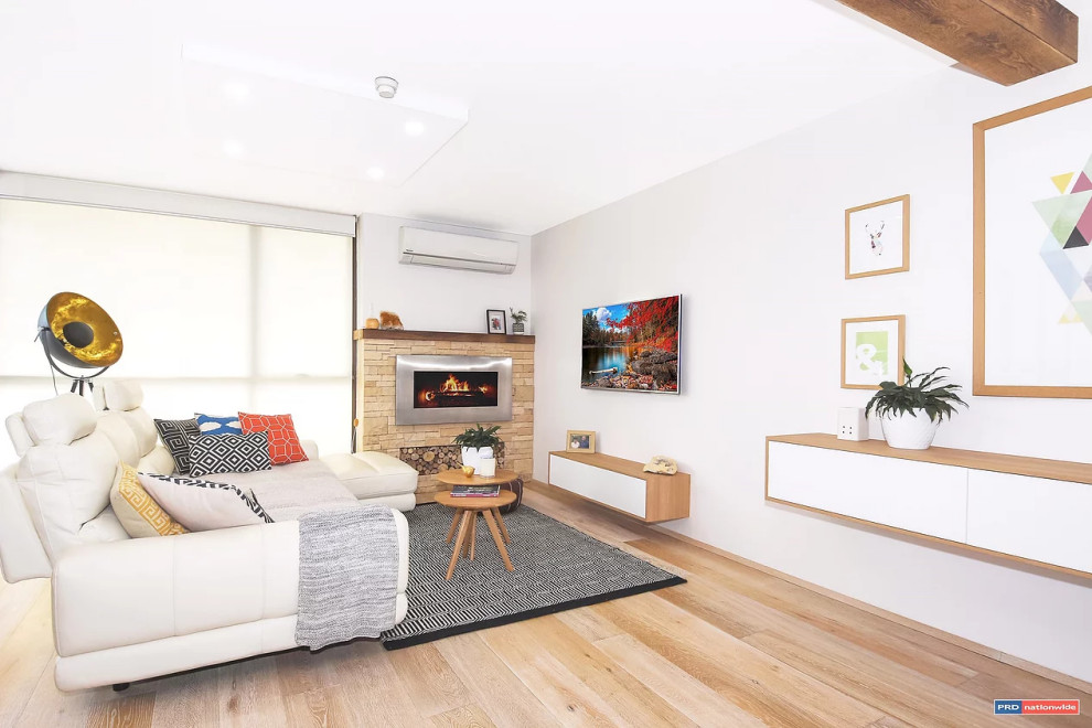 Photo of a mid-sized scandinavian open concept living room in Gold Coast - Tweed with white walls, medium hardwood floors, a stone fireplace surround and beige floor.