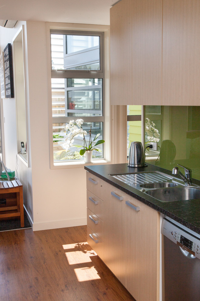 Kitchen - contemporary vinyl floor kitchen idea in Dunedin with light wood cabinets, laminate countertops, green backsplash, glass sheet backsplash and stainless steel appliances
