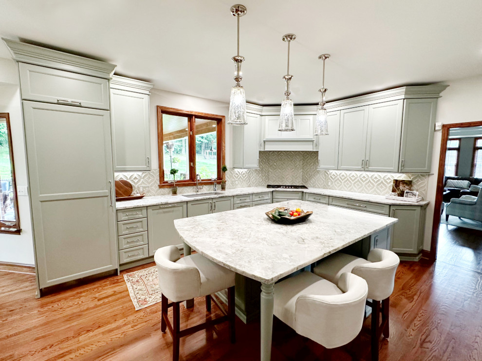 Transitional l-shaped medium tone wood floor eat-in kitchen photo with shaker cabinets, green cabinets, quartzite countertops, porcelain backsplash, paneled appliances and an island