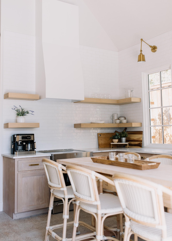 Inredning av ett klassiskt litet vit vitt kök, med en undermonterad diskho, skåp i shakerstil, skåp i ljust trä, bänkskiva i kvarts, vitt stänkskydd, stänkskydd i porslinskakel, rostfria vitvaror, betonggolv, en köksö och grått golv