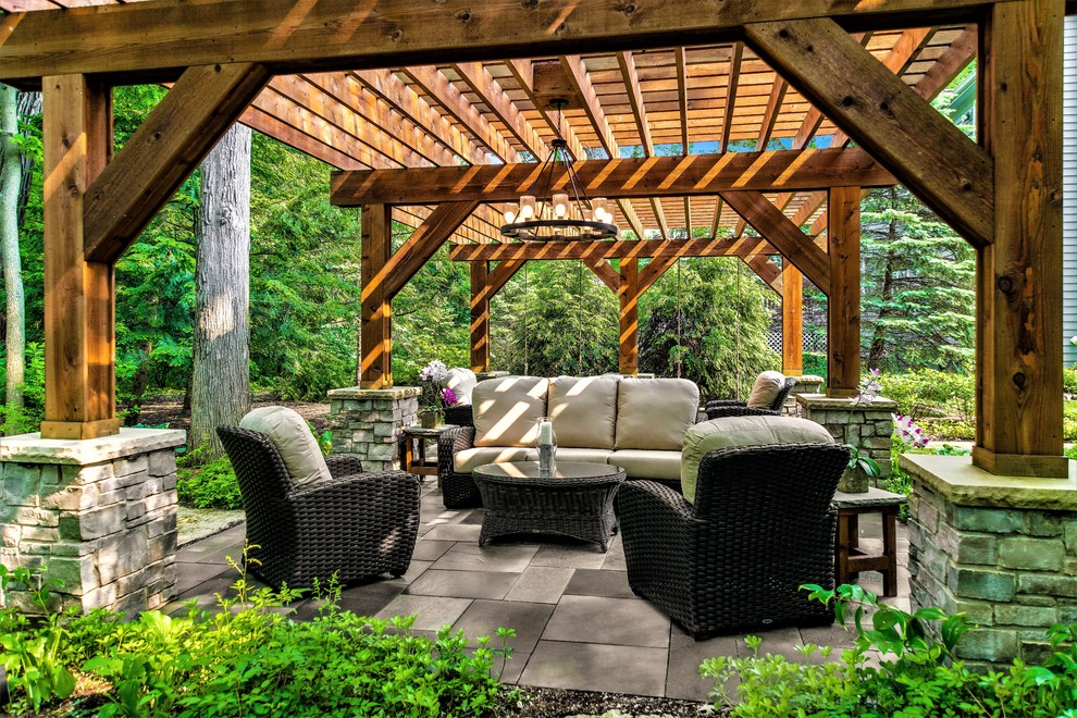 This is an example of a large traditional backyard patio in Chicago with natural stone pavers and a pergola.