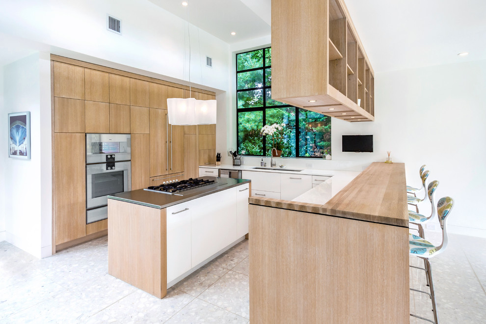 Photo of a mid-sized contemporary u-shaped eat-in kitchen in New York with a double-bowl sink, flat-panel cabinets, light wood cabinets, stainless steel appliances and with island.