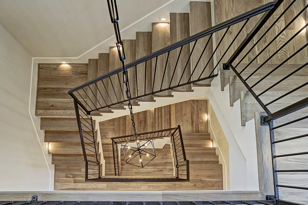 Photo of a large transitional wood curved staircase in Houston with painted wood risers and metal railing.