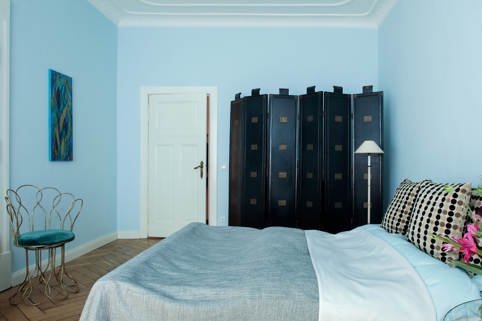 This is an example of a mid-sized eclectic bedroom in Berlin with blue walls, medium hardwood floors and no fireplace.