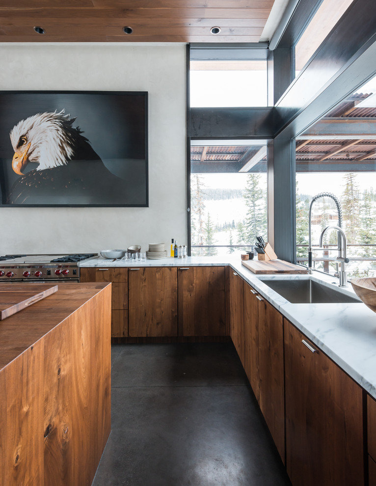 Inspiration for a large country l-shaped eat-in kitchen in Other with an undermount sink, flat-panel cabinets, concrete floors, with island, medium wood cabinets, marble benchtops and stainless steel appliances.