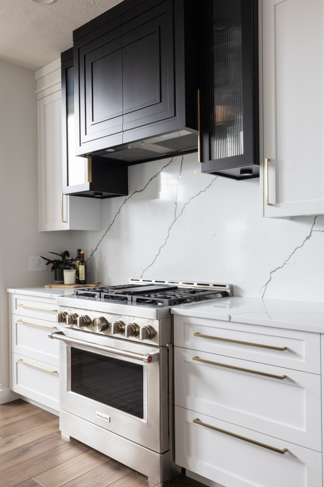 Idéer för ett mellanstort klassiskt svart kök och matrum, med en undermonterad diskho, skåp i shakerstil, vita skåp, bänkskiva i kvarts, vitt stänkskydd, stänkskydd i sten, rostfria vitvaror, vinylgolv, en köksö och brunt golv