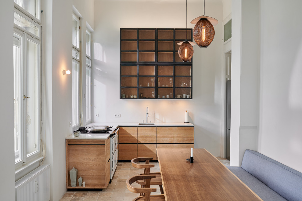 Inspiration for an industrial l-shaped eat-in kitchen in Other with an undermount sink, raised-panel cabinets, light wood cabinets, terrazzo benchtops, white splashback, stainless steel appliances, travertine floors, no island, beige floor and white benchtop.
