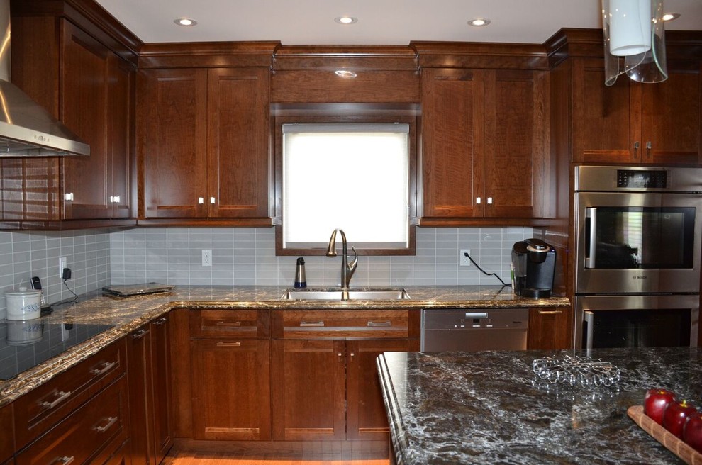 Example of a large transitional l-shaped medium tone wood floor open concept kitchen design in Toronto with an undermount sink, recessed-panel cabinets, dark wood cabinets, quartzite countertops, gray backsplash, glass tile backsplash, stainless steel appliances and an island