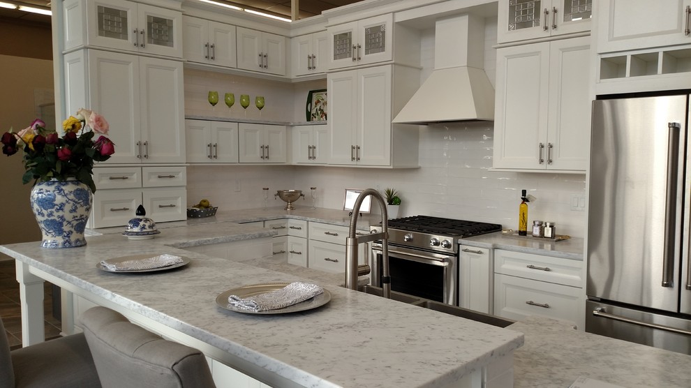 Eat-in kitchen - mid-sized transitional eat-in kitchen idea in New York with a double-bowl sink, white cabinets, marble countertops, white backsplash, ceramic backsplash, stainless steel appliances and an island