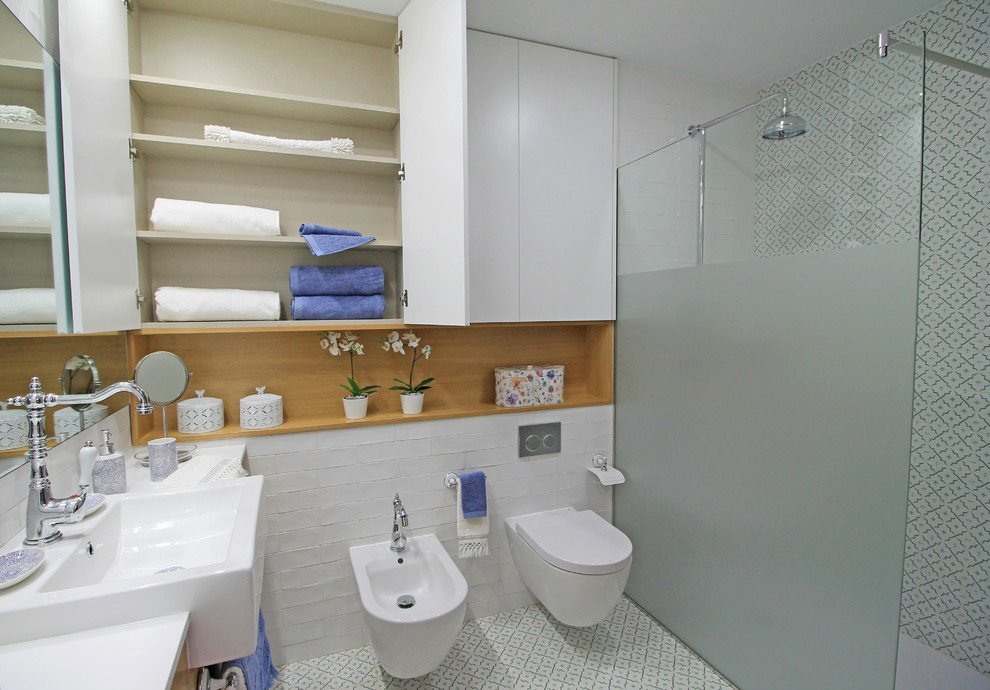 Photo of a large contemporary master bathroom in Valencia with flat-panel cabinets, a curbless shower, a wall-mount toilet, white tile, subway tile, white walls, ceramic floors, a vessel sink, blue floor and light wood cabinets.