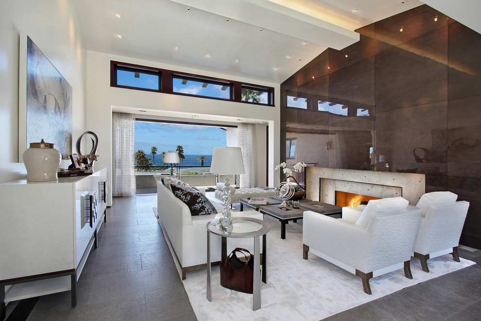 Expansive beach style open concept living room in Los Angeles with white walls, a standard fireplace and a concrete fireplace surround.