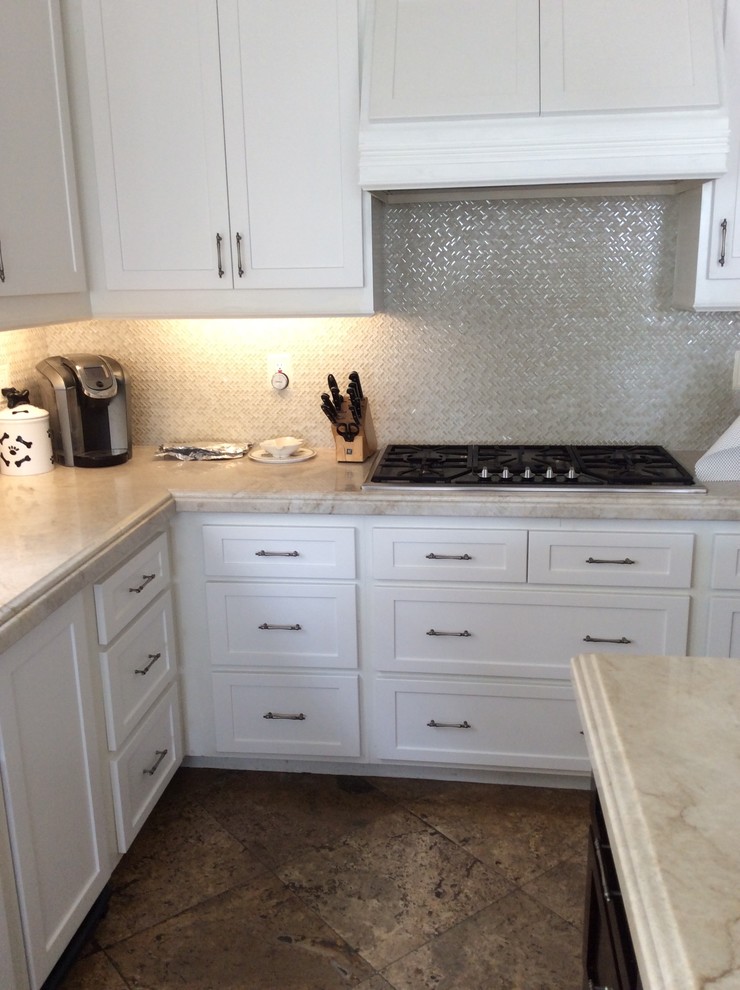 Mid-sized transitional l-shaped travertine floor and brown floor eat-in kitchen photo in Orange County with shaker cabinets, white cabinets, marble countertops, beige backsplash, mosaic tile backsplash, stainless steel appliances and an island