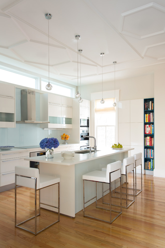 Inspiration for a mid-sized contemporary galley open plan kitchen in Boston with an undermount sink, flat-panel cabinets, white cabinets, solid surface benchtops, blue splashback, glass sheet splashback, stainless steel appliances, medium hardwood floors and with island.