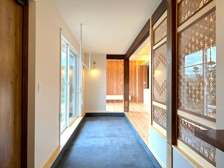 Design ideas for a medium sized hallway in Other with white walls, a single front door, a medium wood front door, black floors, a wallpapered ceiling and wallpapered walls.