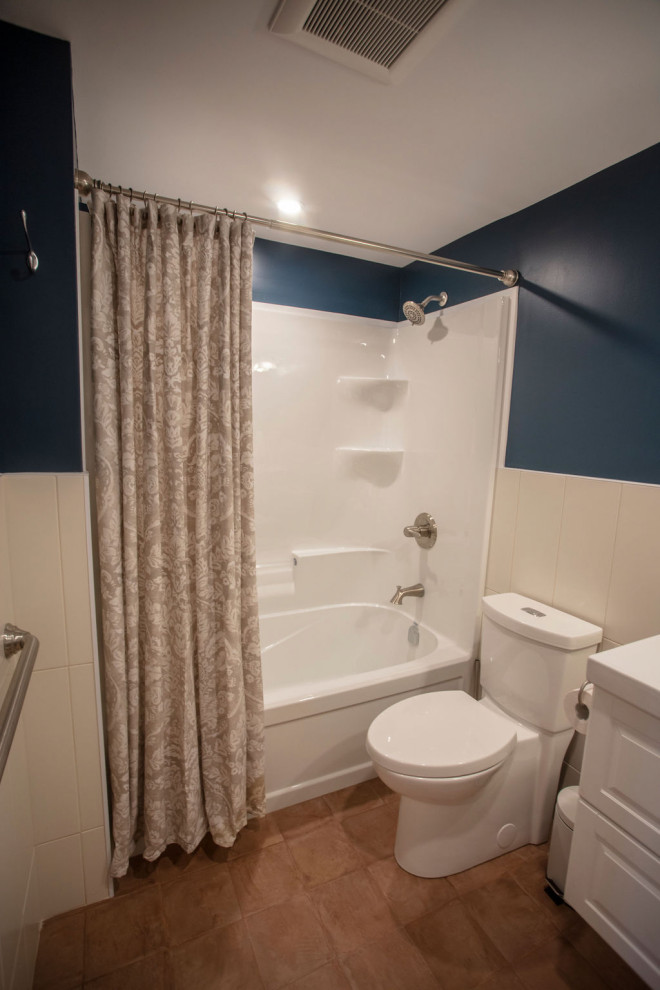 Klassisk inredning av ett litet vit vitt badrum, med skåp i shakerstil, vita skåp, ett badkar i en alkov, en dusch/badkar-kombination, en toalettstol med separat cisternkåpa, vit kakel, porslinskakel, blå väggar, klinkergolv i porslin, ett integrerad handfat, brunt golv och dusch med duschdraperi