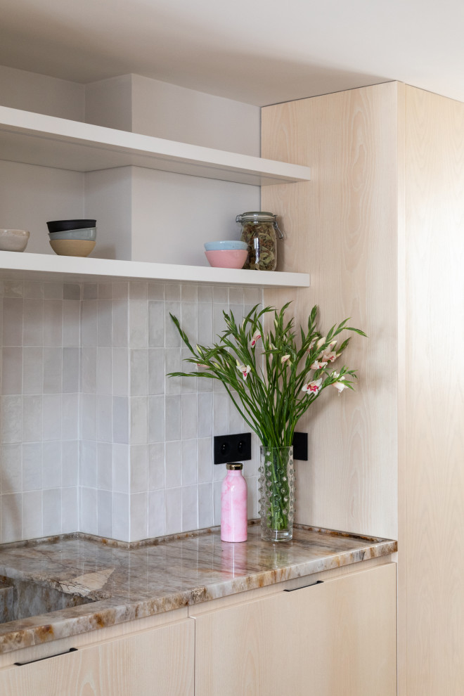 Inspiration pour cuisine ouverte in U and bois clair With un évier intégré, un placard à porte plane, un plan de travail en quartz, une crédence blanche, une crédence en céramique, un électroménager noir, un sol en carrelage de céramique, îlot, un sol beige and un plan de travail beige.