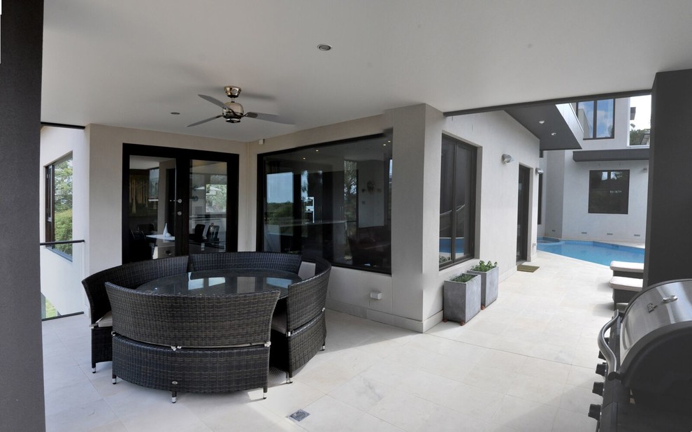 Photo of a small contemporary side yard patio in Melbourne with natural stone pavers and a roof extension.
