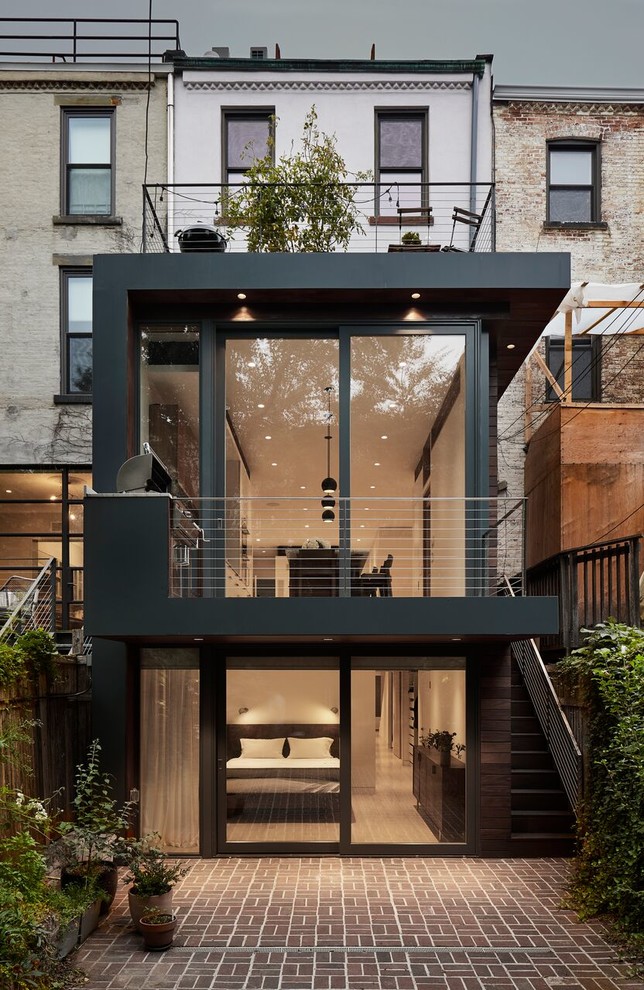 Design ideas for a mid-sized contemporary three-storey black townhouse exterior in New York with mixed siding, a flat roof and a green roof.