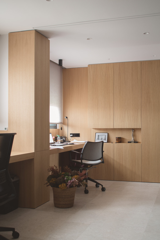 Ejemplo de despacho moderno de tamaño medio con suelo de piedra caliza, escritorio empotrado y madera