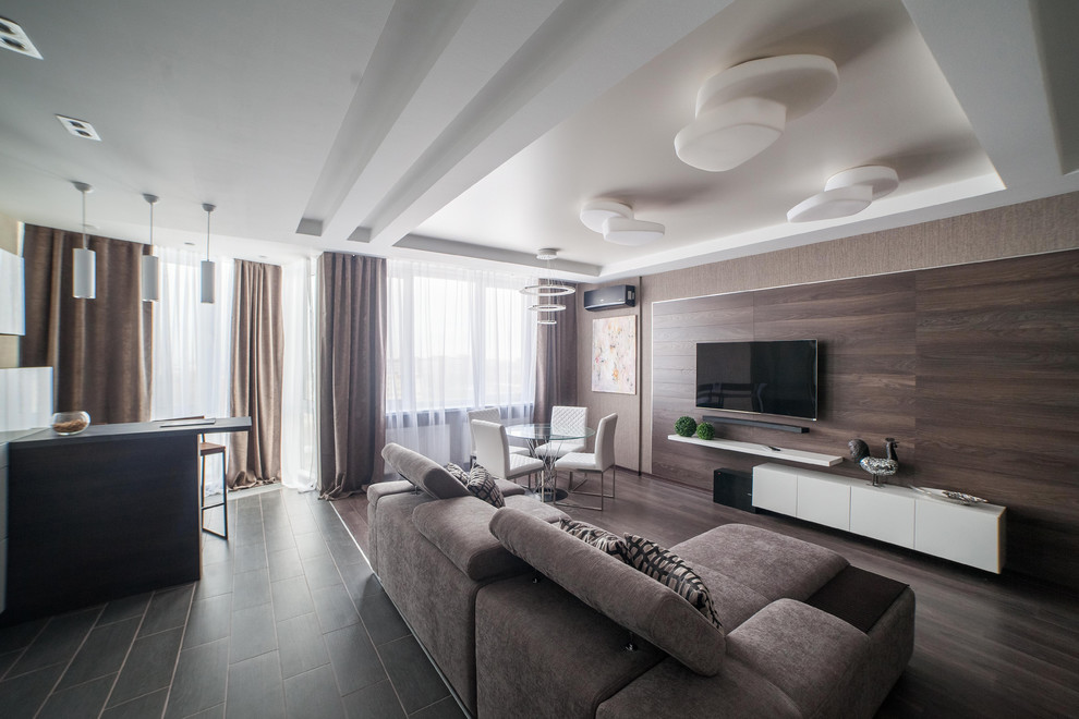 На фото: большая открытая гостиная комната в современном стиле с бежевыми стенами, телевизором на стене, темным паркетным полом, коричневым полом и музыкальной комнатой