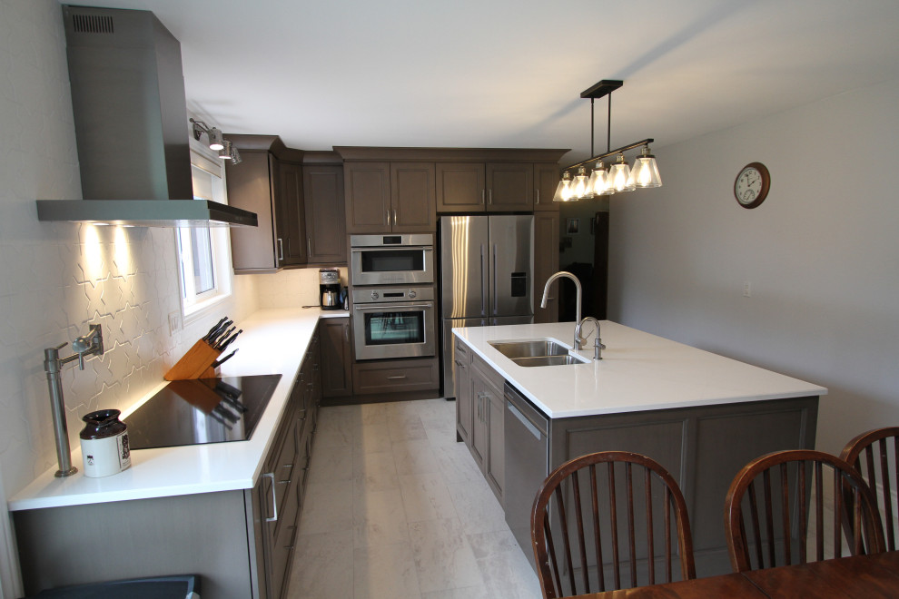 This is an example of a medium sized contemporary l-shaped kitchen/diner in Toronto with a submerged sink, recessed-panel cabinets, brown cabinets, engineered stone countertops, white splashback, stainless steel appliances, porcelain flooring, an island, grey floors and white worktops.
