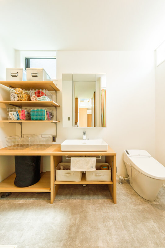 Idéer för mellanstora funkis beige toaletter, med öppna hyllor, en vägghängd toalettstol, vit kakel, vita väggar, ljust trägolv, ett fristående handfat, beiget golv, vita skåp och bänkskiva i betong